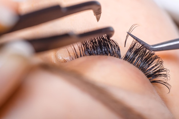 Eyelash extension procedure woman eye with long eyelashes lashes close up macro selective focus