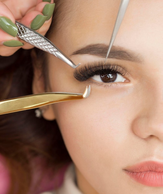 Eyelash Extension Procedure. A woman's eye with long eyelashes. Eyelashes, close-up, macro, selective focus. Tweezers. Beautiful girl on eyelash extension procedure