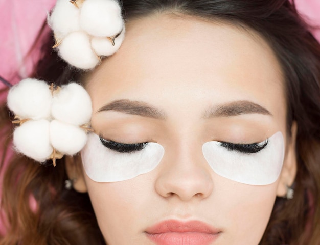 Eyelash extensions. Artificial eyelashes. The girl in the salon is doing an eyelash extension procedure. Close-up.