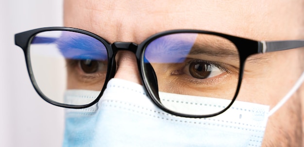 Photo eyes of a male doctor in glasses and a medical mask healthcare concept and medicine closeup