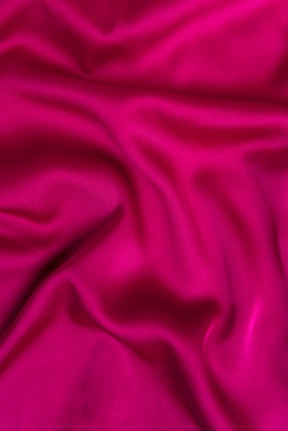 Fabric fuchsia or crimsoncolored color Texture of bright pink tissue silk or satin Abstract backgroundVertical frame