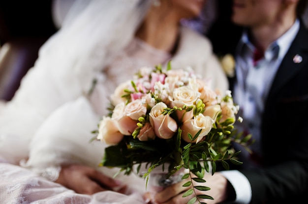 Fabulous wedding couple posing and kissing in the car.