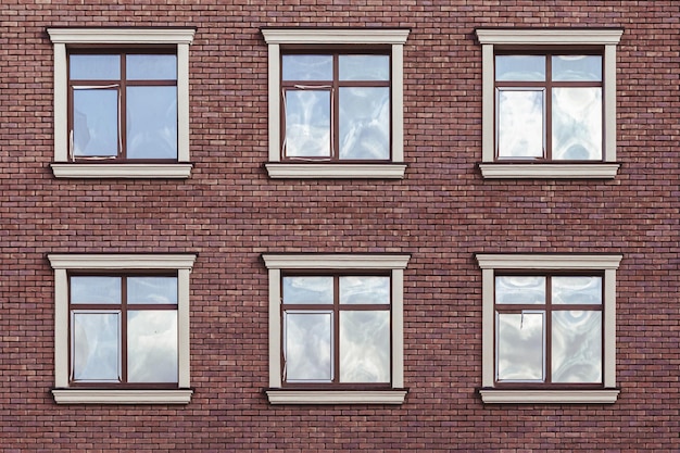 The facade of a brick house with identical square windows Facade of the house Brick wall