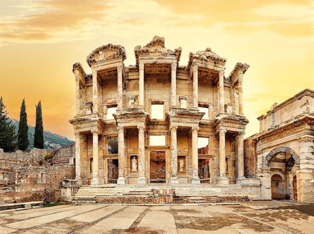 Facade of the library of Celsus in Ephesus under a yellow sunset sky. Turkey. Panorama