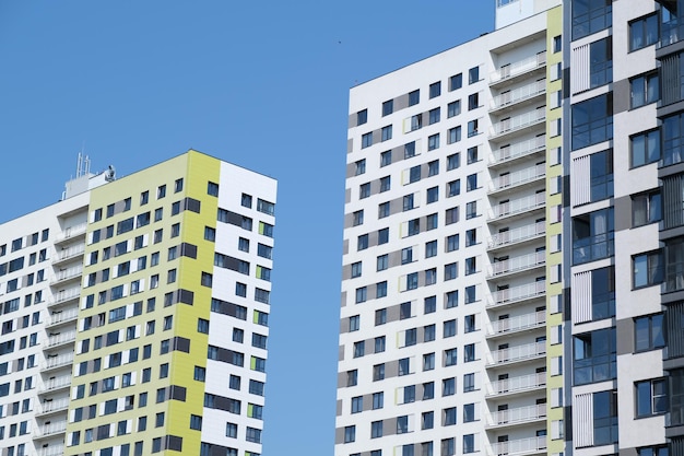 Facade of modern building in city From below of contemporary high rise buildings with glass mirrored windows against cloudless blue sky