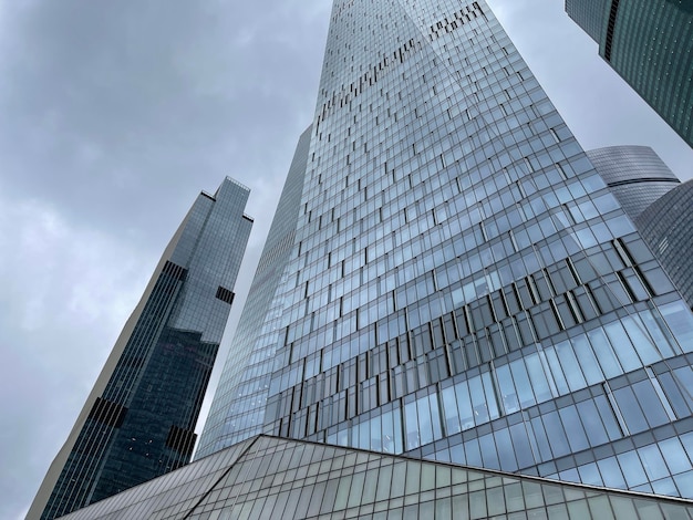 Facade of modern skyscraper with glass walls From below of contemporary tall skyscraper with glass walls against cloudy sky in downtown