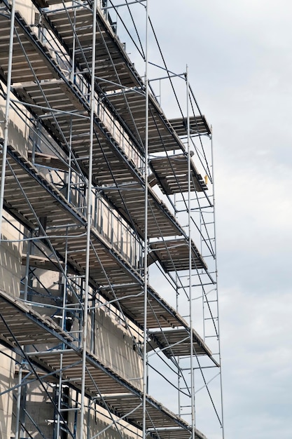 Facade restoration of building against cloudy sky Reconstruction of building exterior with scaffolding