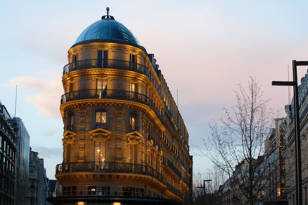 The facade of traditional French house with typical balconies and windows at evening Paris