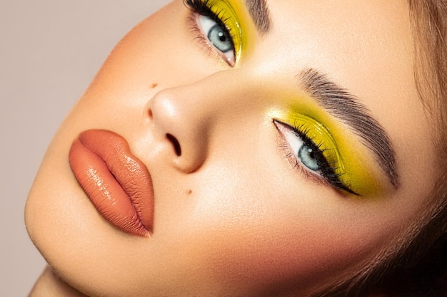 Face of a blueeyed female model with vibrant makeup and a hoot look