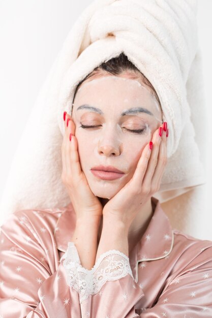 Face care and beauty treatments Woman with a sheet moisturizing mask on her face isolated on white background