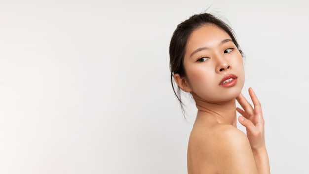 Face care concept portrait of young sensual asian lady looking back at copy space over white