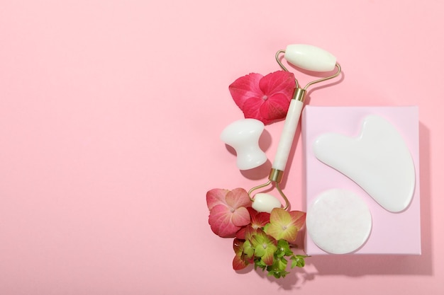 Face care concept with gua sha kit on pink background