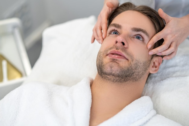 Face care. Young male client having face massage in a professional salon