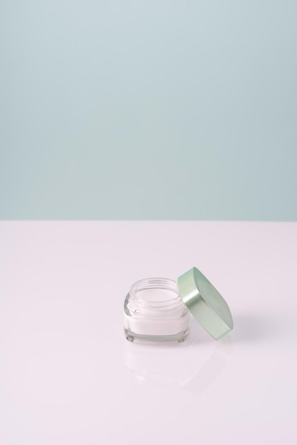 Face cream in a glass container on a whiteblue background