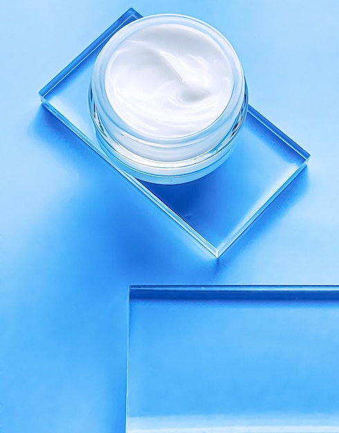 Face cream moisturiser jar on glass and blue background beauty product and skincare cosmetic science