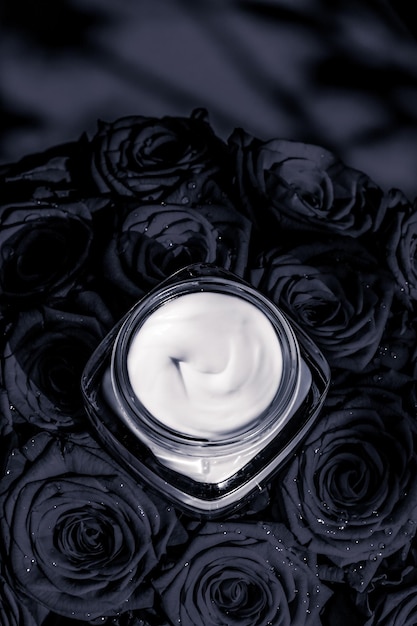 Face cream skin moisturizer and black roses flowers luxury skincare cosmetic product on floral background as beauty brand holiday flatlay design