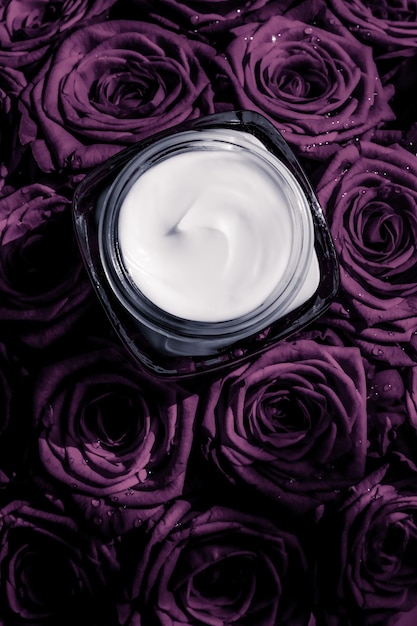 Face cream skin moisturizer on purple roses flowers luxury skincare cosmetic product on floral background as beauty brand holiday flatlay design