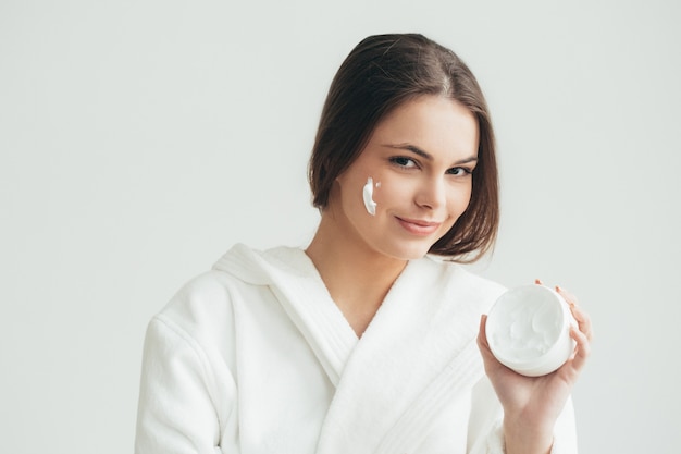 Face cream woman applying crean on skin natural portrait. Studio shot.