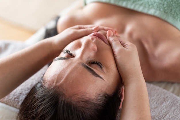 Face of the girl closeup the massage therapist makes massage Green background