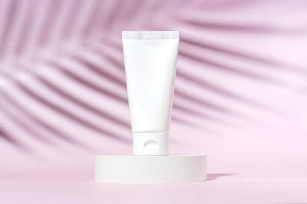 Face or hand cream in a white plastic tube on a pink background with shadow of a tropical palm tree Womens cosmetic accessory for makeup Mockup identity copy space