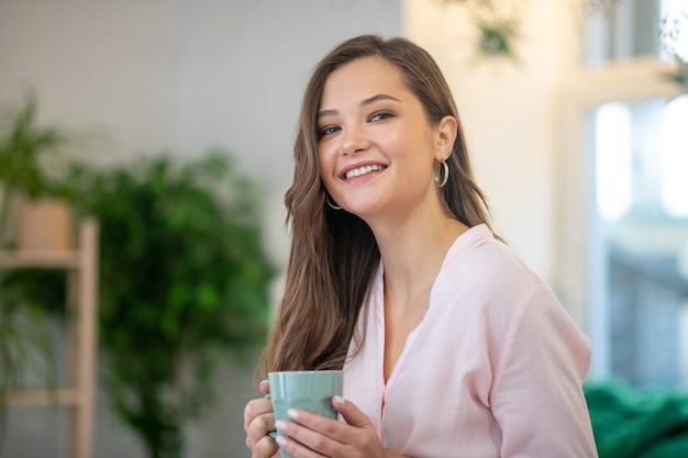 Face of a joyful young woman feeling full of energy while drinking coffee