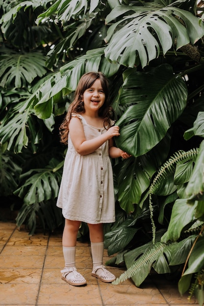 The face of a little girl surrounded by tropical leaves Portrait of a beautiful baby with perfect skin and dark hair closeup Natural cosmetics health cleanliness skin care beauty concept