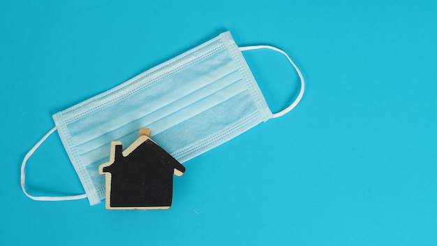 Face mask or medical mask and little black wooden home board sign on black background.