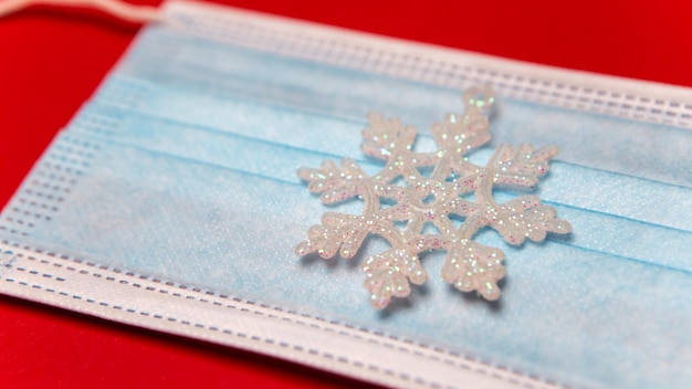 Face mask with snowflake toy on red background