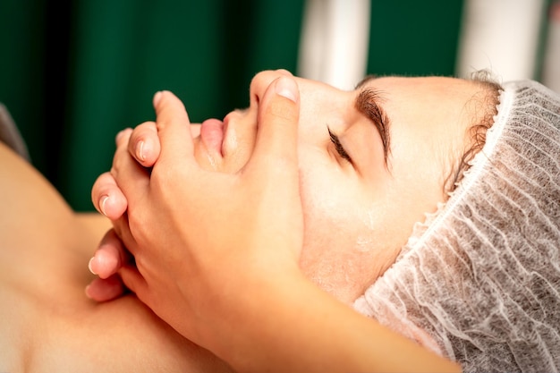 Face massage Beautiful caucasian young white woman having a facial massage with closed eyes in a spa salon