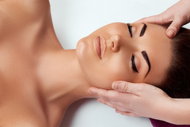 Face massage. Close-up of young woman getting spa massage treatment at beauty spa salon