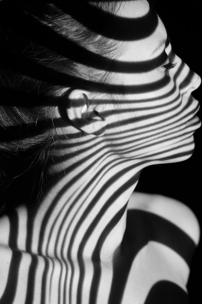 The face of nude woman  with black and white zebra stripes.  Black-and-white photo created with the projector