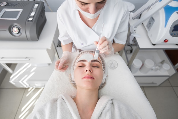 Face peeling mask, spa beauty treatment, skincare. Woman getting facial care by beautician at spa salon