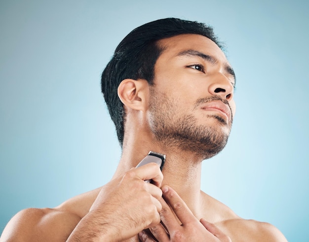 Face shaving and electric razor with a man in studio on a blue background for personal hygiene skincare or grooming Beauty wellness or cosmetics with a young male in the bathroom for hair removal