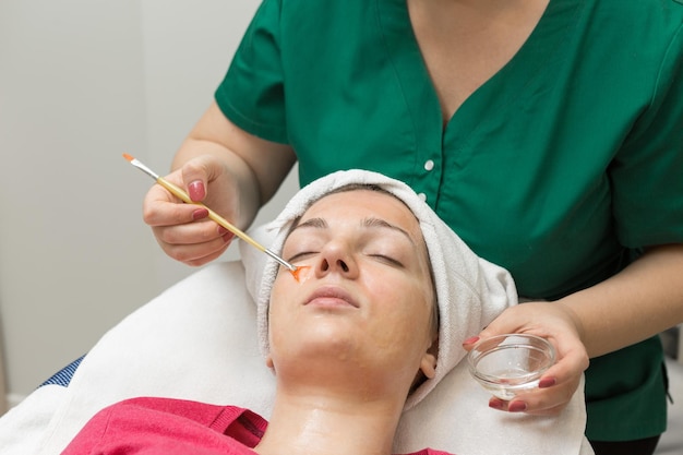 Face skin care Beautician applying beauty oil mask on face using brush In spa salon