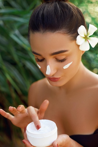 Face Skincare Beauty and Spa Concept Portrait of female holding moisturizing cream in her hand