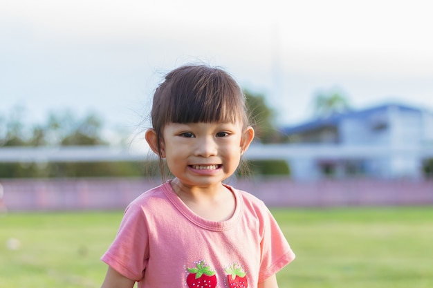 Face of smiling Asian girl in head shot Happy kid playing at the park playground