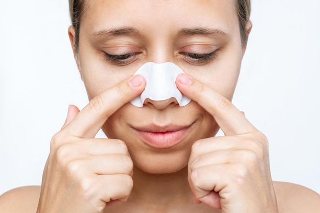 The face of woman cleaning the skin of her nose with strips from blackheads and looking down