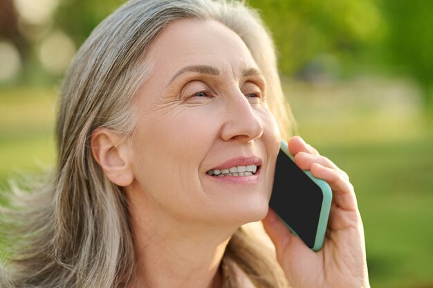 Face of woman of retirement age talking on smartphone