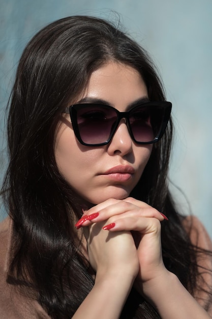 Face of young hipster with plump lips and long hair looks at camera through dark sunglasses