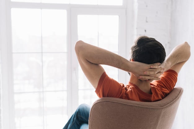 Faceless man relaxing in armchair