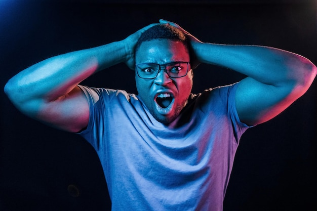 Facial expression Futuristic neon lighting Young african american man in the studio