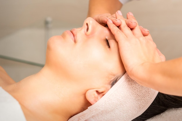 Facial massage young caucasian woman with closed eyes getting a massage on her forehead in a beauty