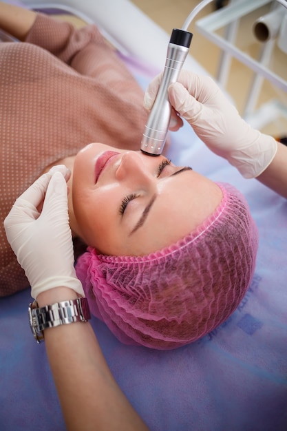 Facial skin care. Young beautiful woman with gets procedure in a beauty salon. Ultrasonic anti-aging cavitation, rejuvenation, lifting procedure. Beauty concept