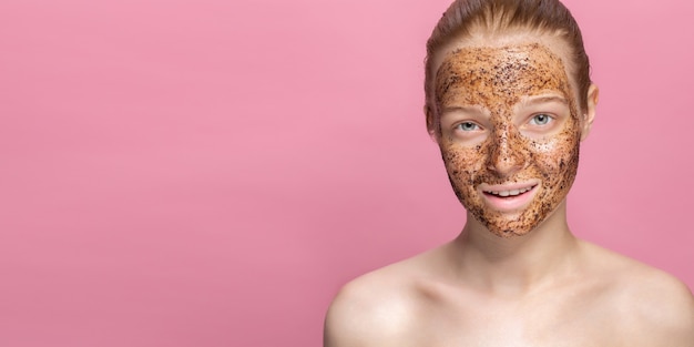 Photo facial skin scrub coffee grounds mask on the face of a beautiful young woman