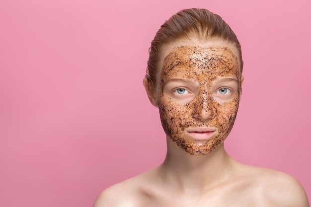 Photo facial skin scrub coffee grounds mask on the face of a beautiful young woman