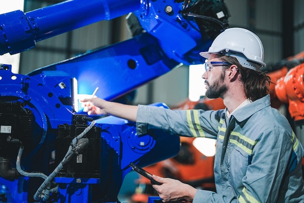 Factory engineer inspecting on machine with smart tablet Worker works at heavy machine robot arm The welding machine with a remote system in an industrial factory Artificial intelligence concept