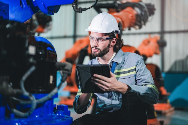 Factory engineer inspecting on machine with smart tablet Worker works at heavy machine robot arm The welding machine with a remote system in an industrial factory Artificial intelligence concept