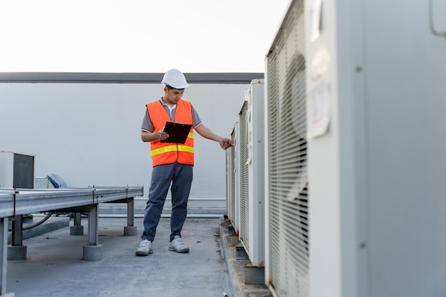 Factory engineers walking and checking the cooling system of the factory Fore man records the condition of the compressor before maintenance according maintenance plan