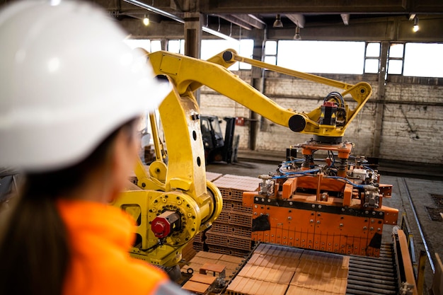 Factory worker observing manufacturing process while industrial machines working in background