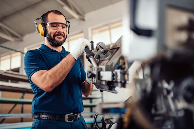 Factory worker operating band saw cutting machine